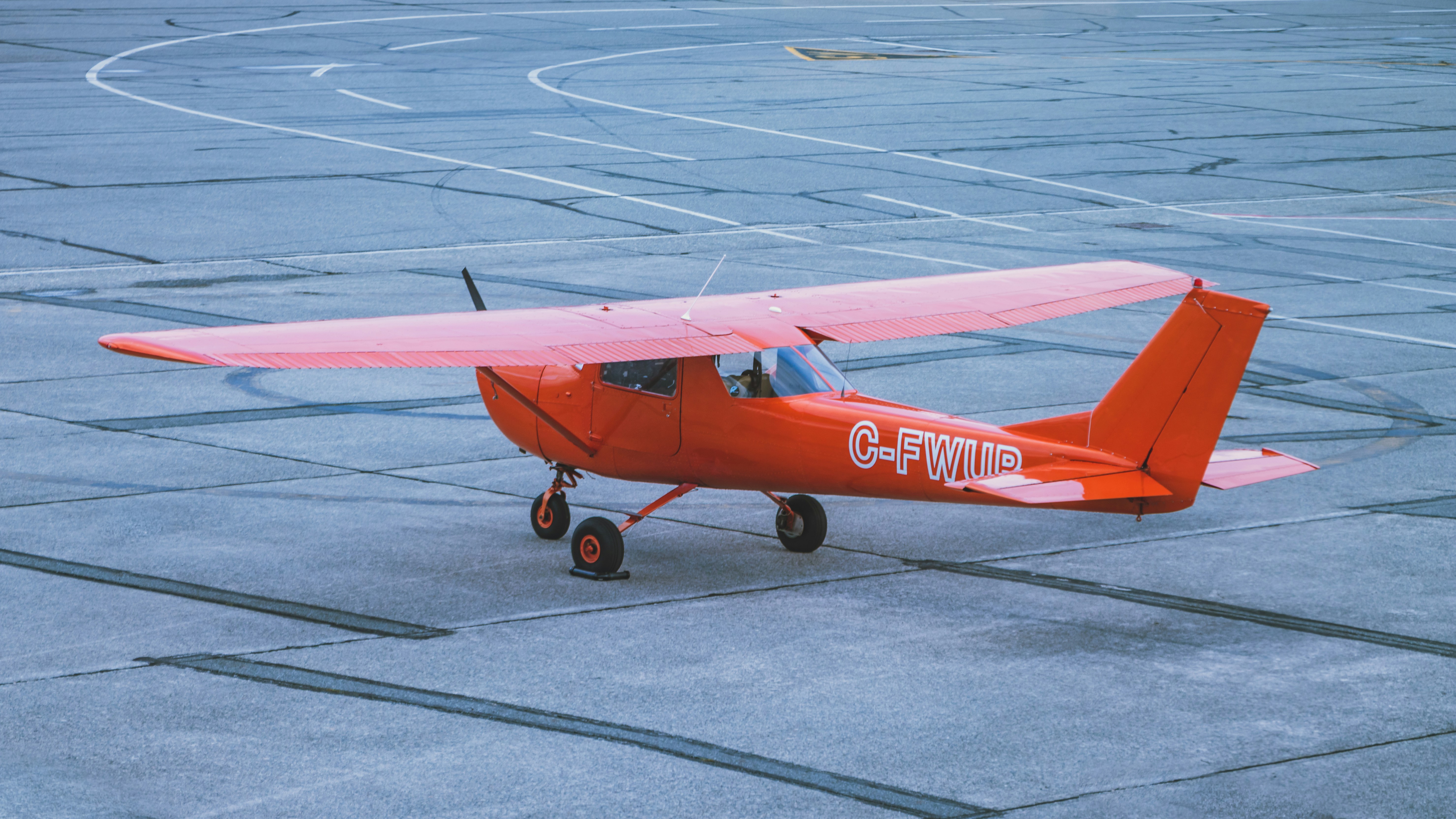 small orange aircraft waiting on airport tarmac next to runway